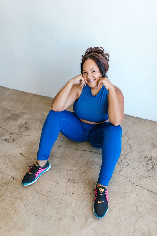 Person in blue athletic clothes sitting down and smiling at the camera
