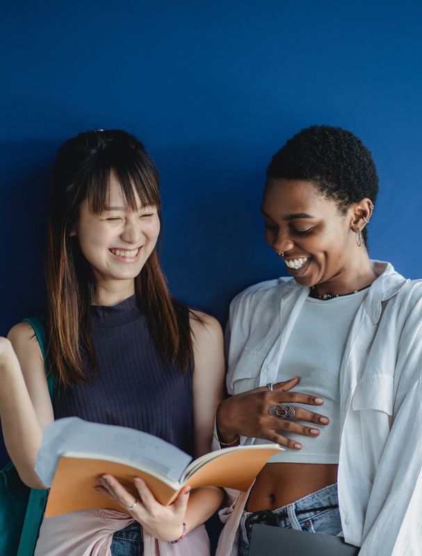 Two people looking at a book together and laughing
