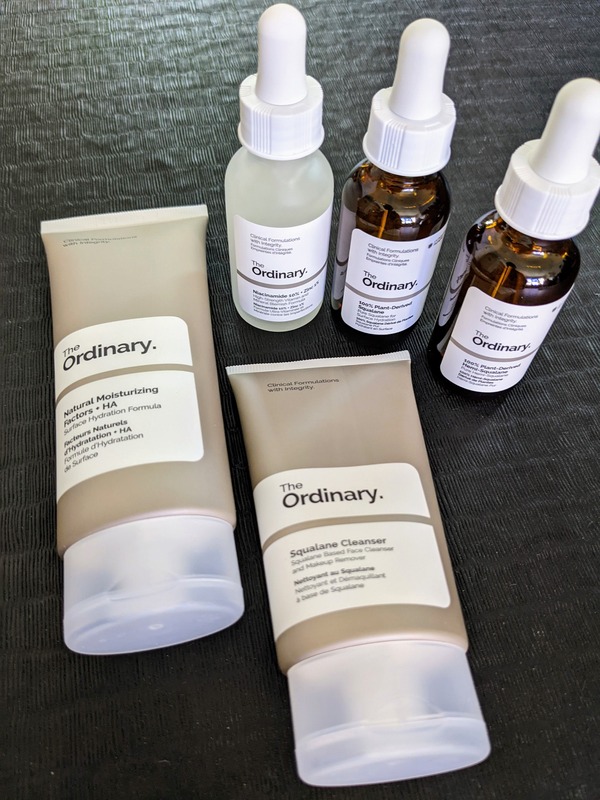 5 The Ordinary gender neutral skincare products photographed on a black surface