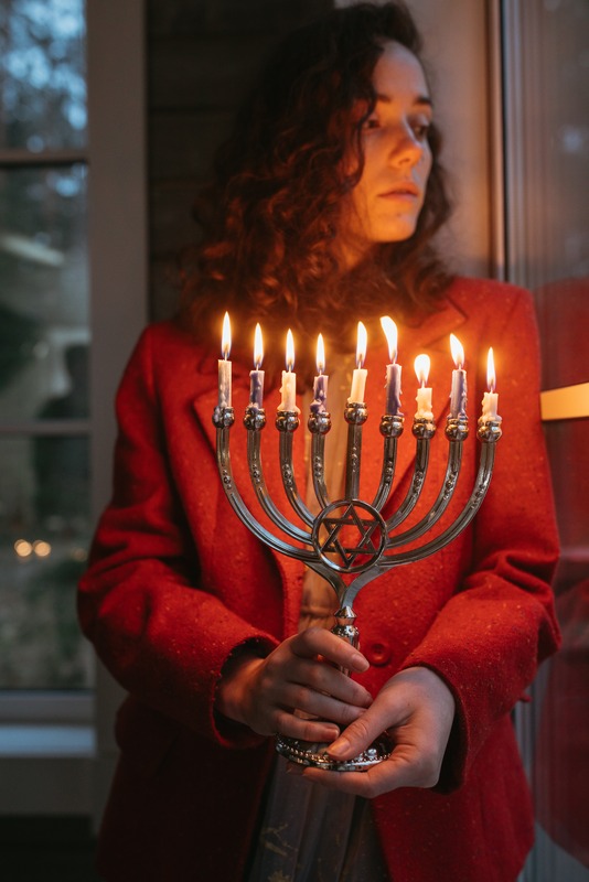 Person holding a menorah with all candles lit